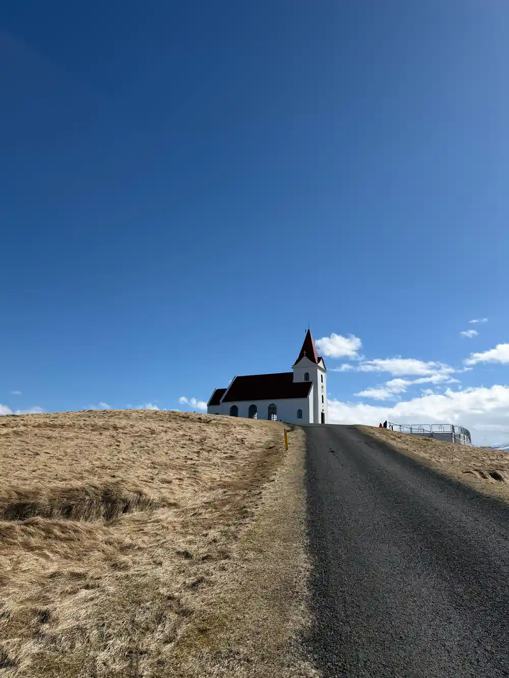 Black church with white tower on dirt road