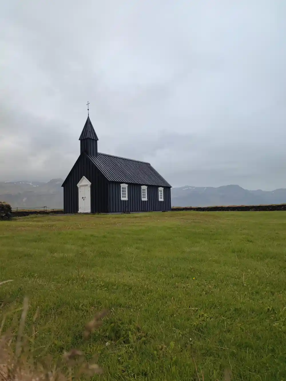 Black wooden church in empty green meadow landscape