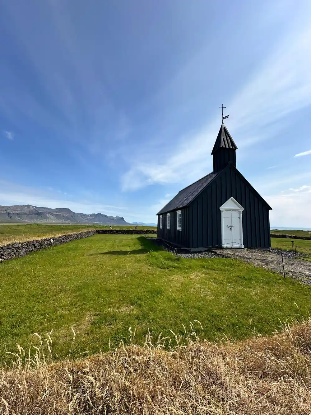 Black wooden church with white door on green grassland