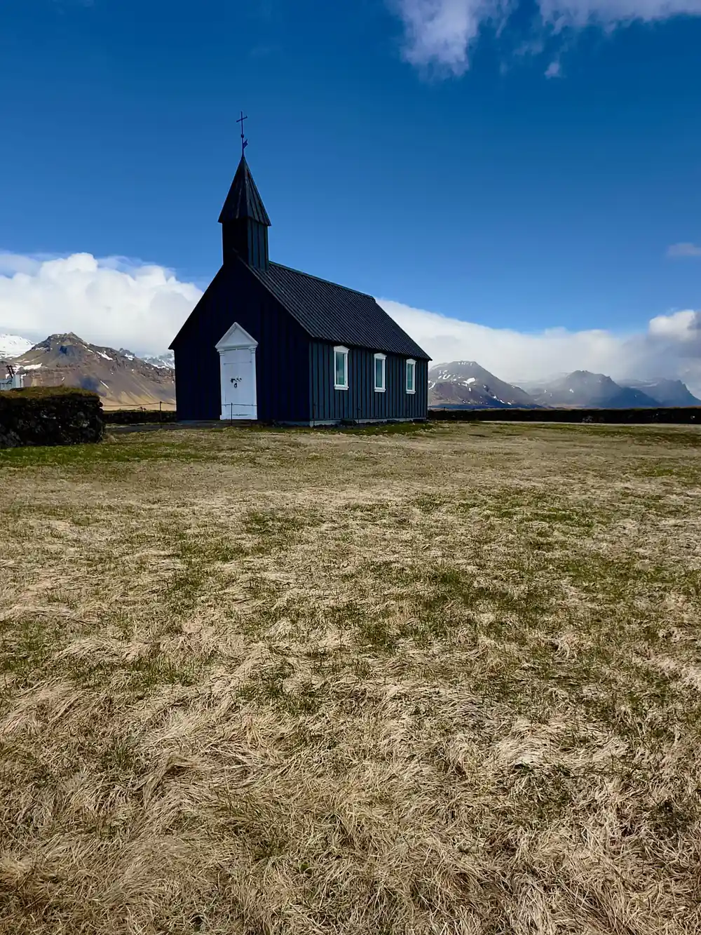 Black wooden church with white trim and mountains
