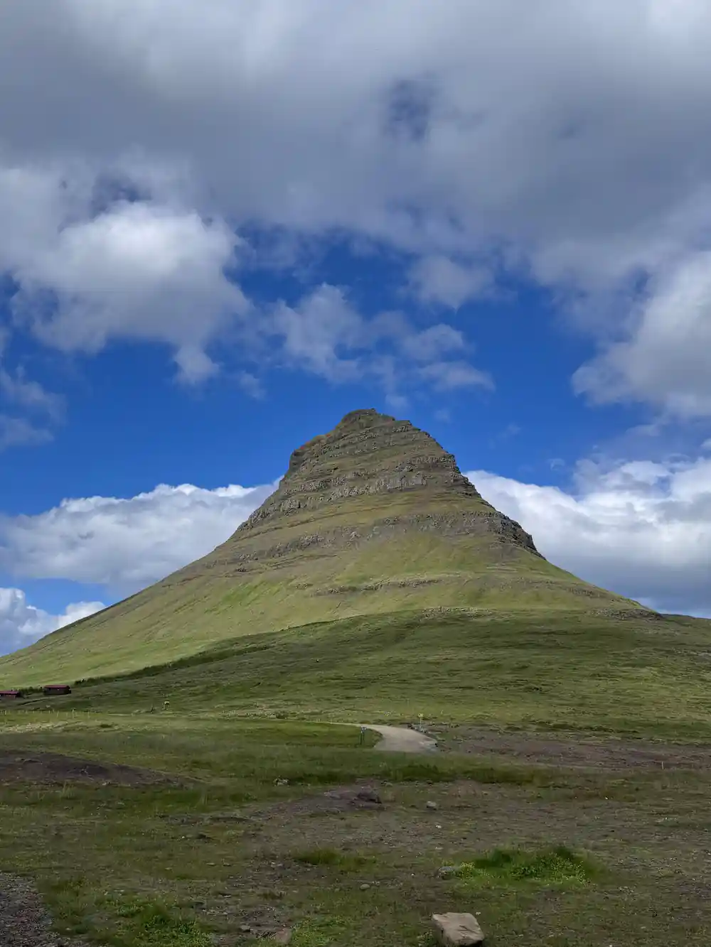 Conical green-and-grey mountain peak under bright sky