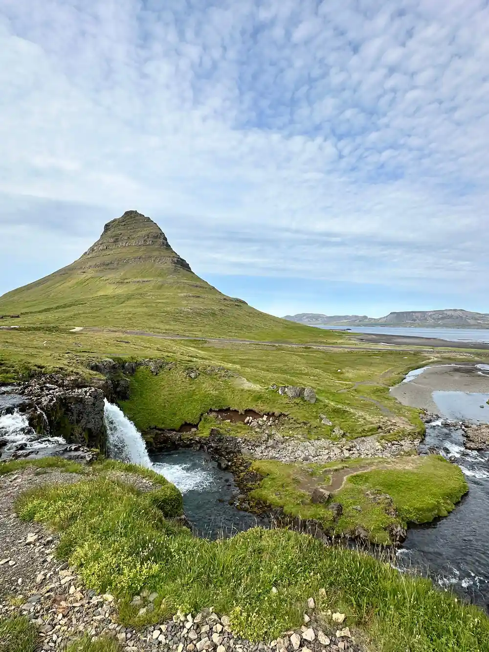 Conical moss-covered mountain with waterfall and stream
