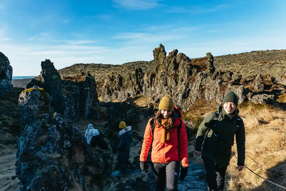 Group hiking among tall basalt rock formations