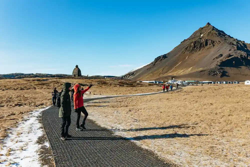 Hikers on wooden boardwalk with mountain and geothermal area