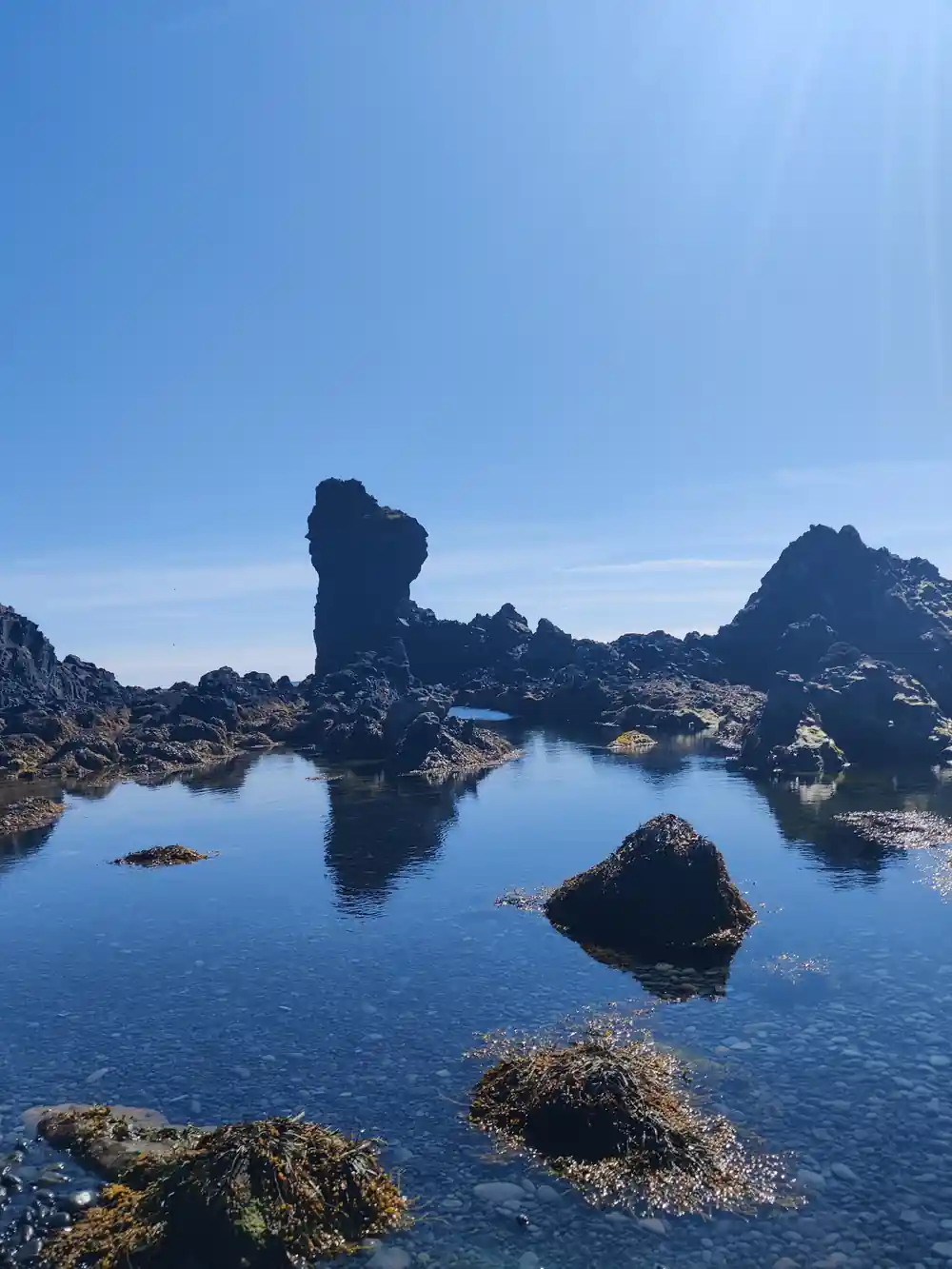 Jagged rock formations rising from still blue pool water