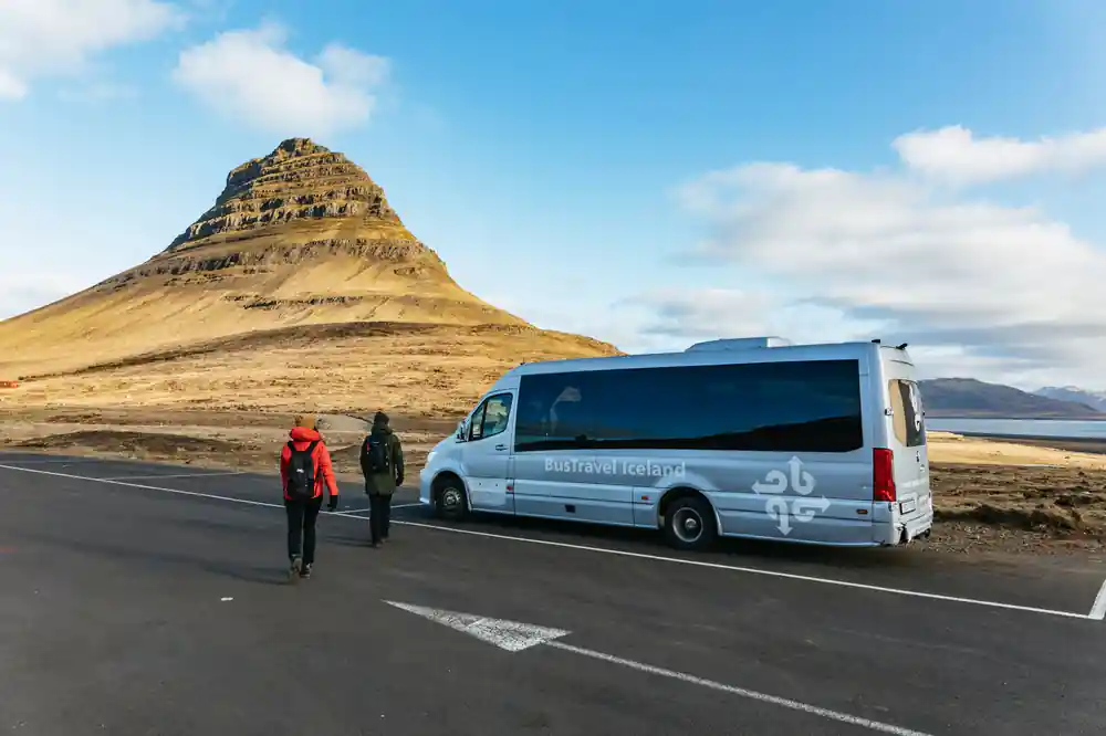 Minibus parked on road with people and distinctive cone mountain