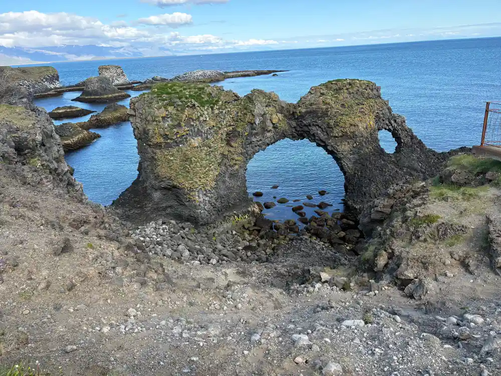 Moss-covered rock formation with natural arch over water