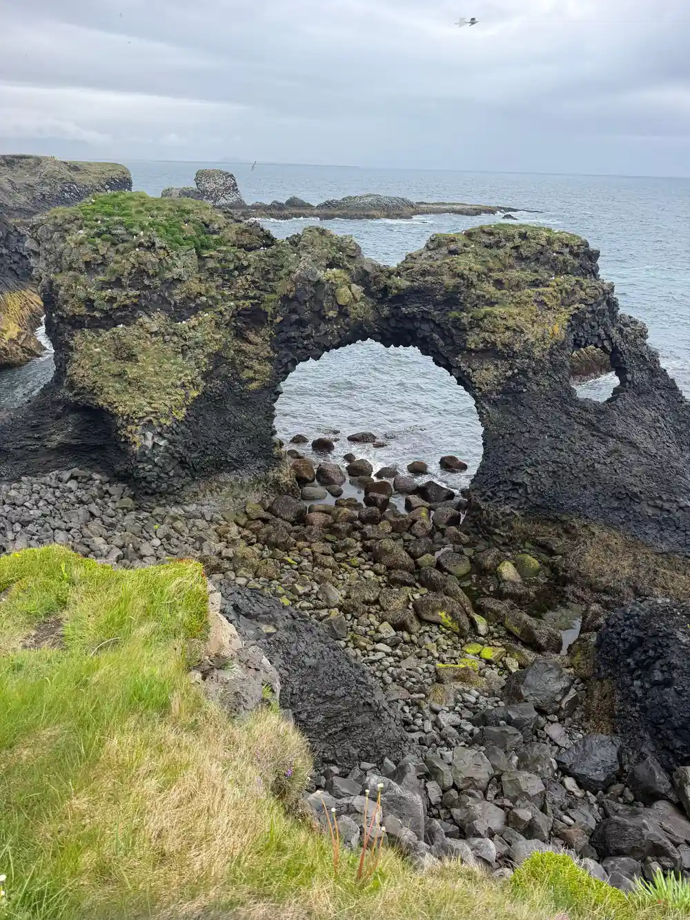 Natural rock arch formation with moss-covered volcanic rocks