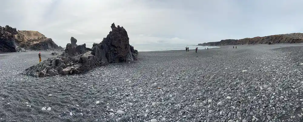 Pebble beach with black lava rock formations in sea