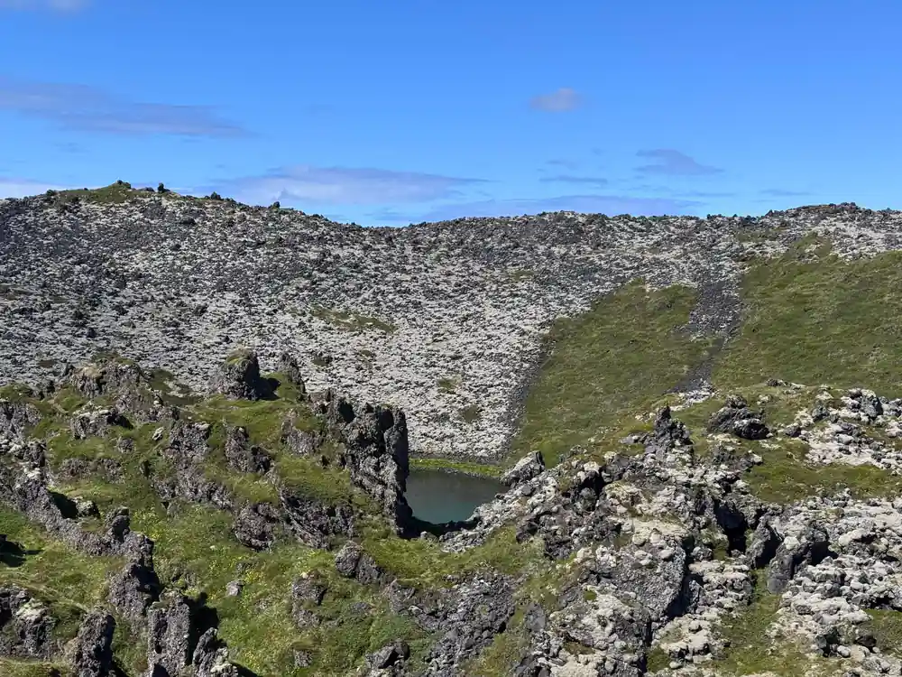 Rocky hillside with small tarn pool and green vegetation