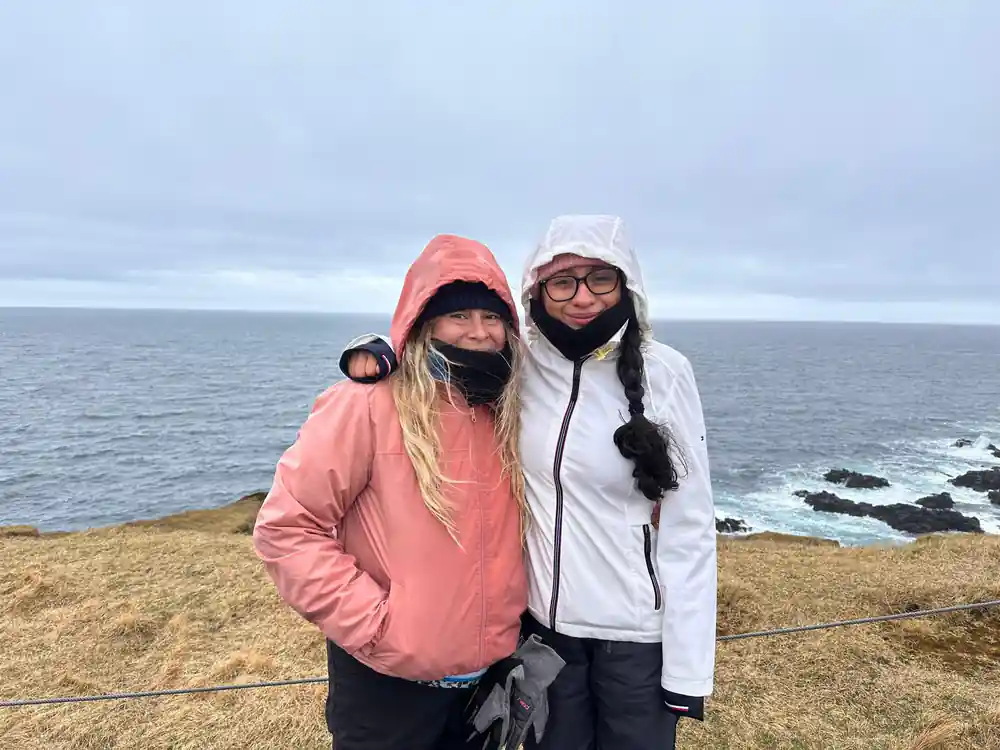 Two women in winter clothing posing by ocean