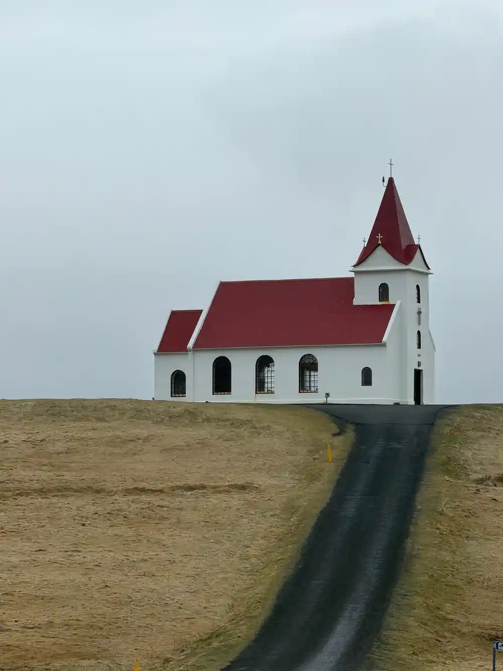 White church with red roof on grassy hillside